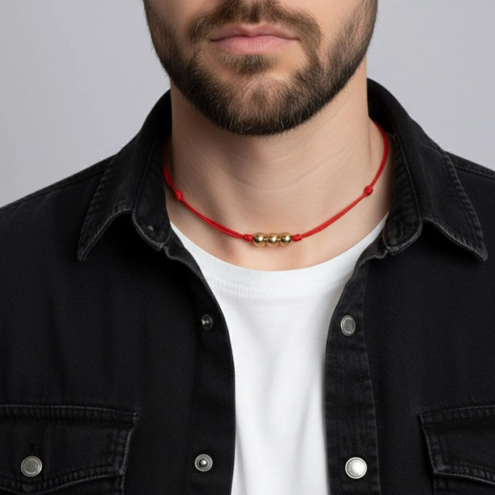 Man wearing a red beaded necklace with gold accents against a gray background