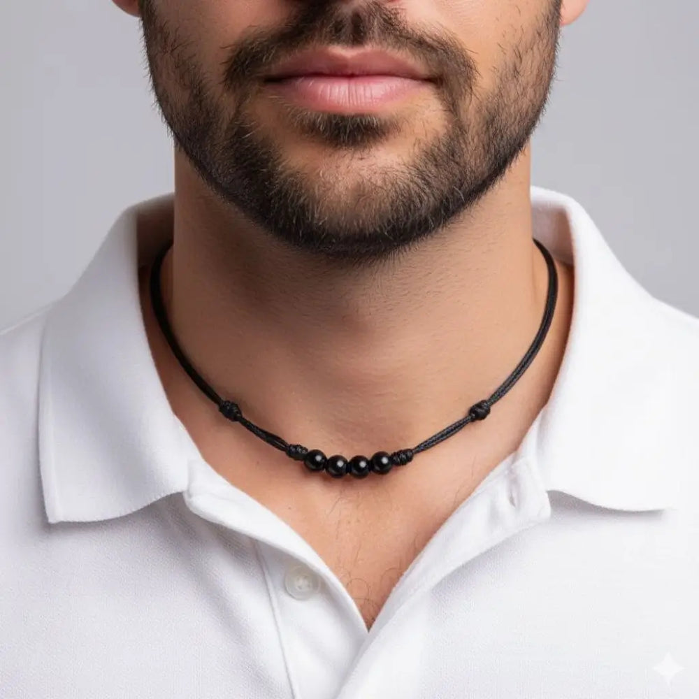 Man wearing a black tourmaline beaded necklace against a plain background