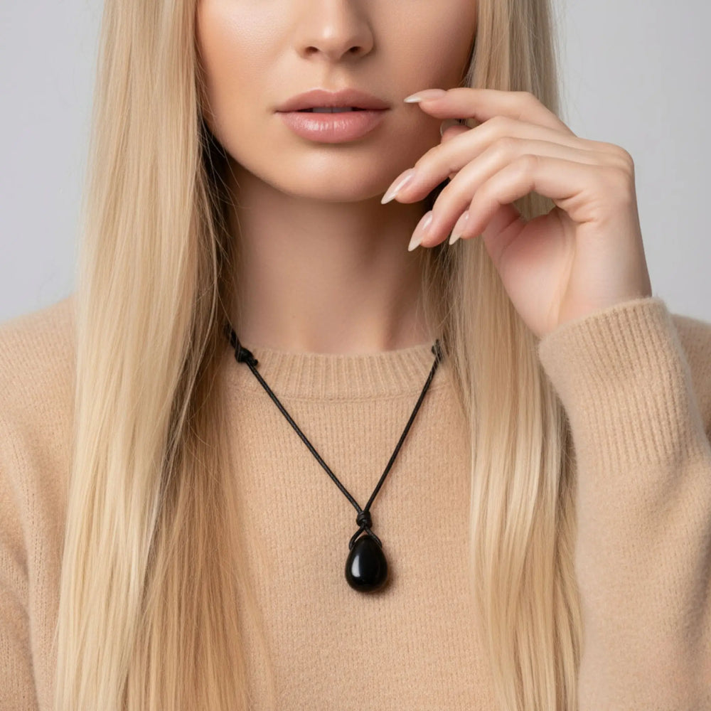 Woman wearing a black tourmaline necklace with a pendant against a neutral background