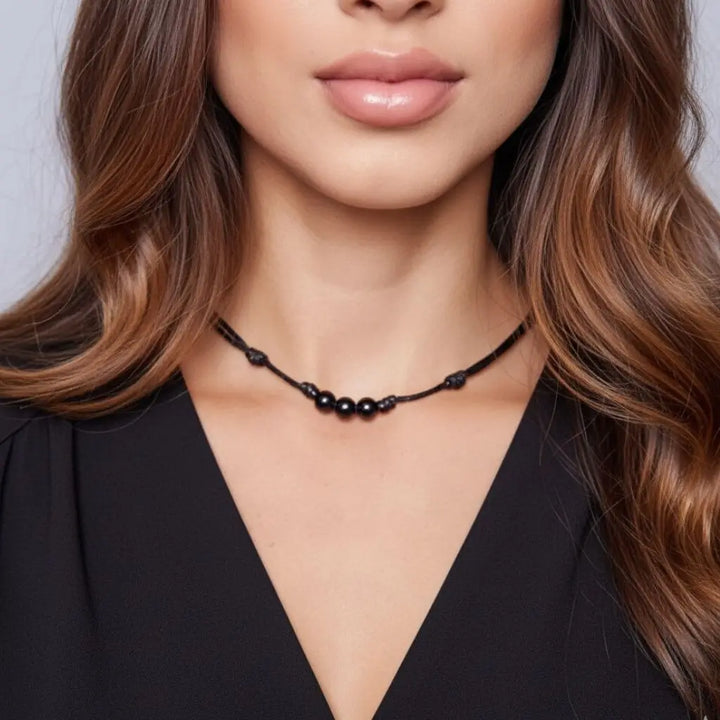 Woman wearing a black tourmaline beaded necklace against a neutral background