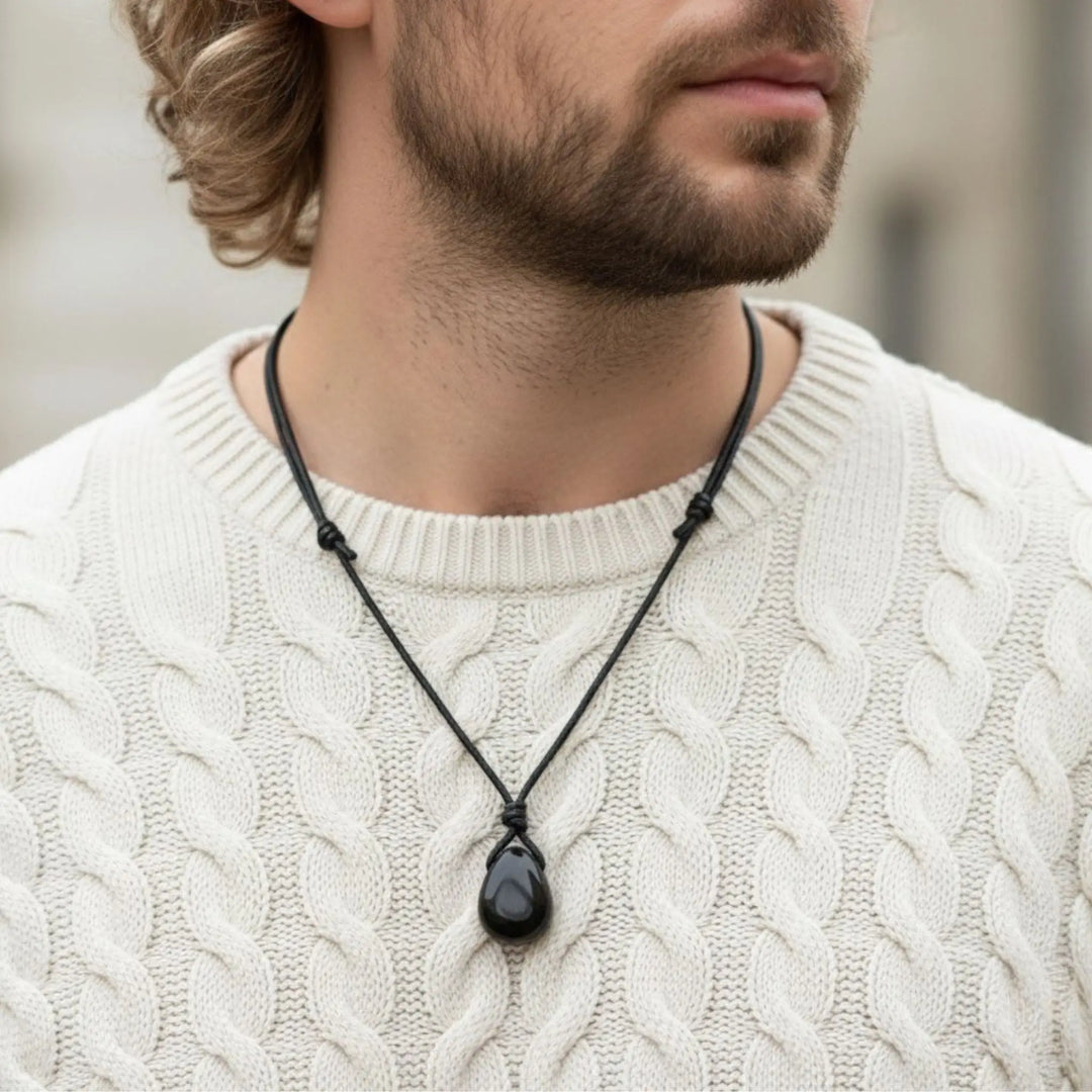 Man wearing a black tourmaline necklace with a pendant on a blurred background