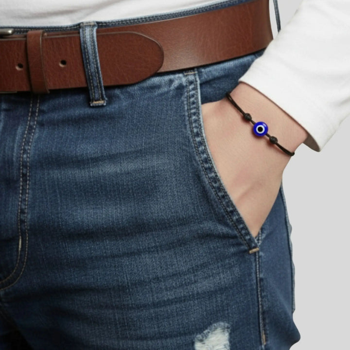 Person wearing a blue evil eye bracelet on a plain background