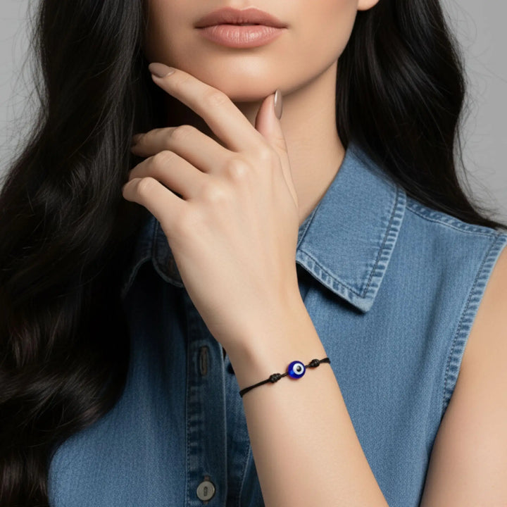 Woman wearing a blue evil eye bracelet on a gray background