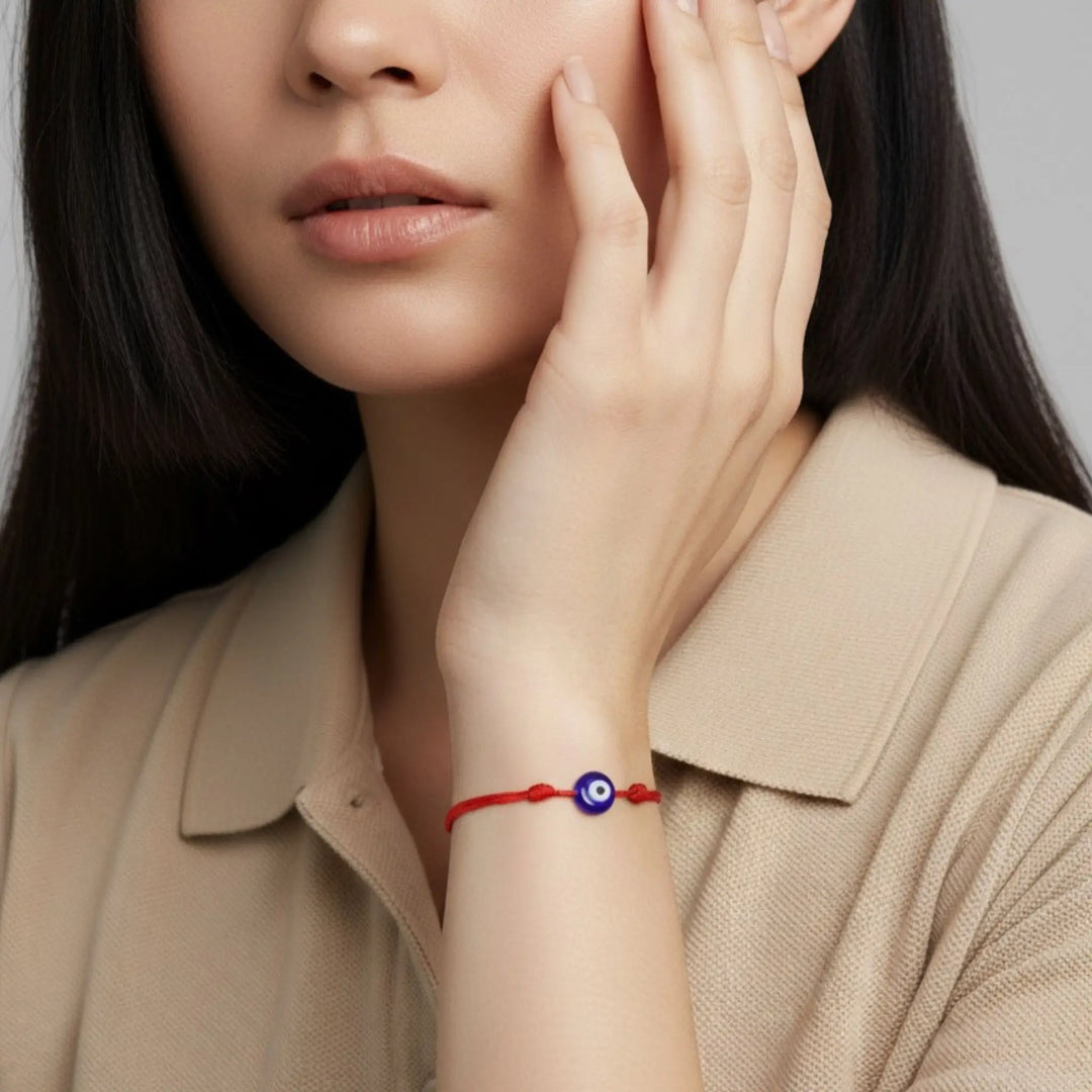 Woman wearing a red bracelet with a blue eye design on a neutral background