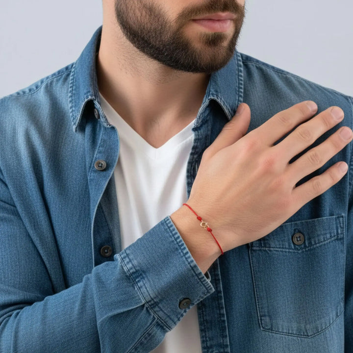 Man wearing a blue denim jacket and white shirt with a red bracelet on his wrist.
