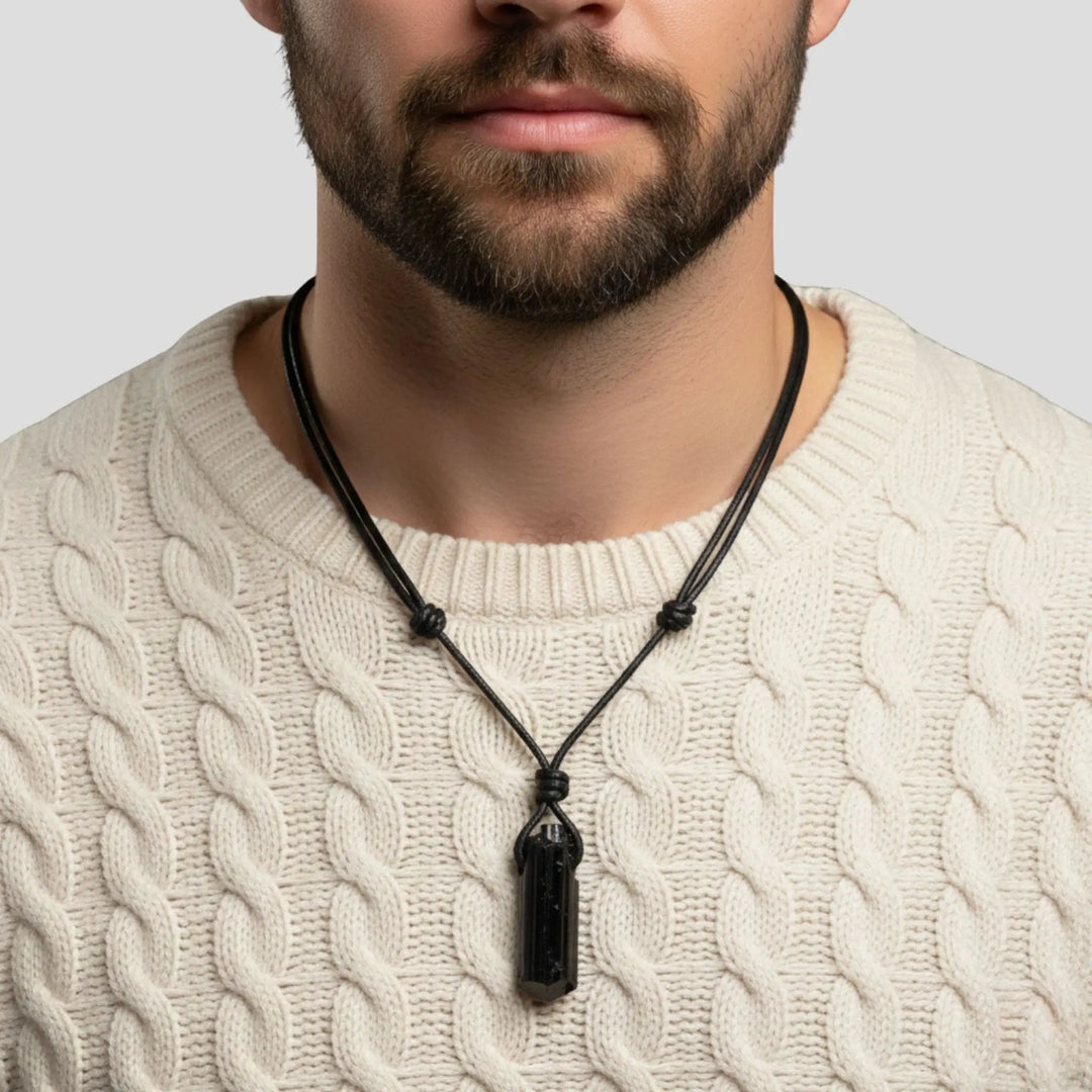 Men wearing a black tourmaline necklace with a pendant on a plain background
