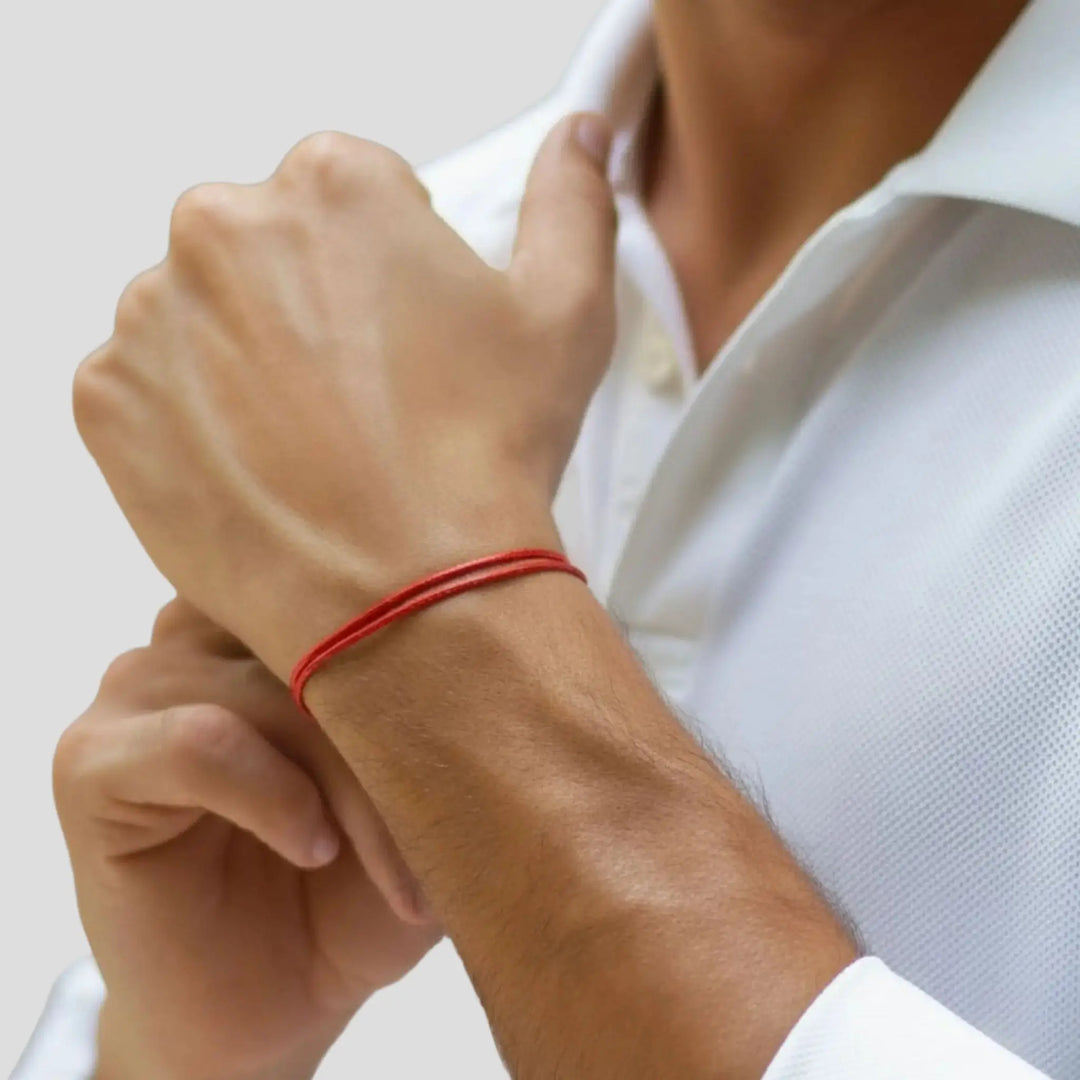 Person wearing a red bracelet on a white background