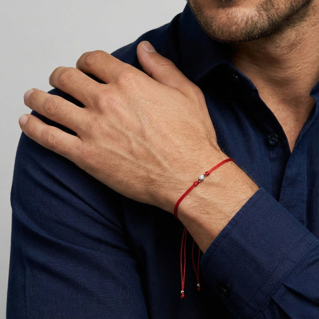 Person wearing a red  diamond bracelet on a plain background
