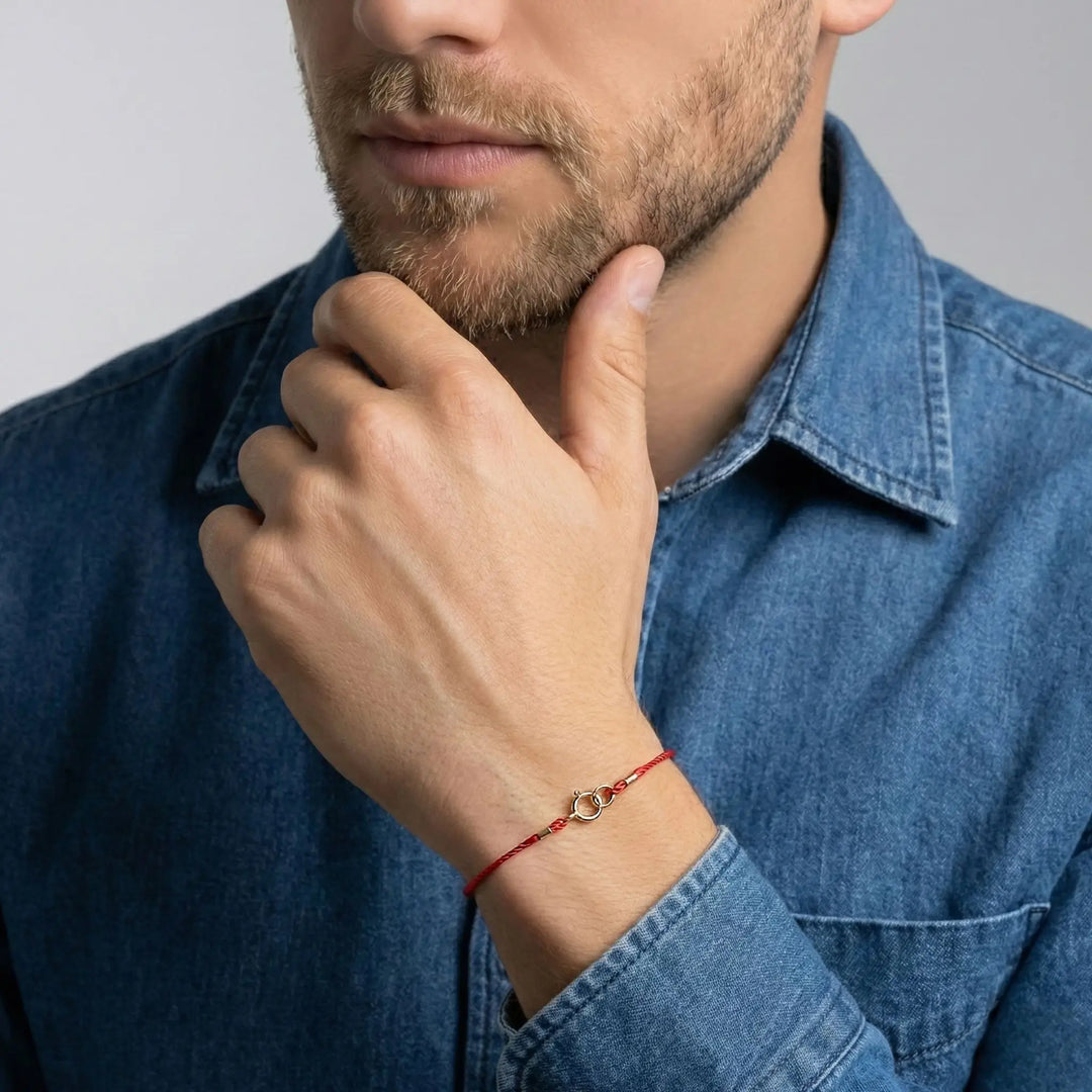 Man wearing a red bracelet on his wrist, with a blurred background
