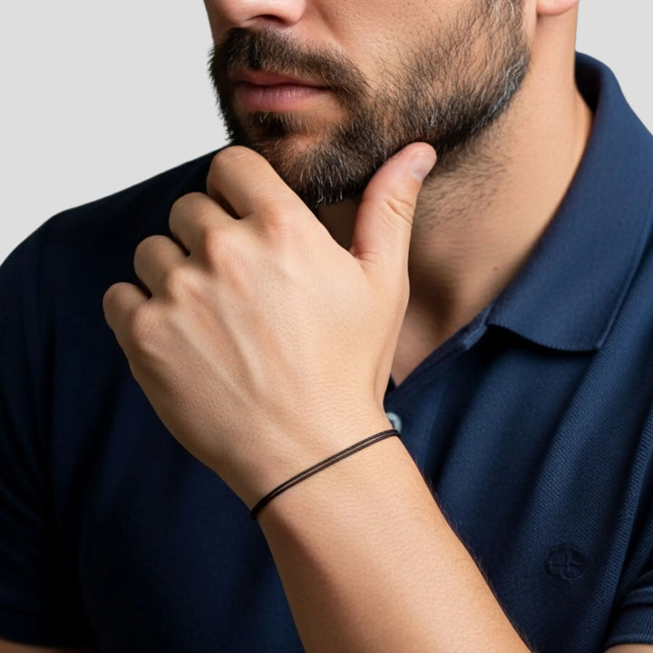Man wearing a dark blue polo shirt with a close-up of his black bracelet 