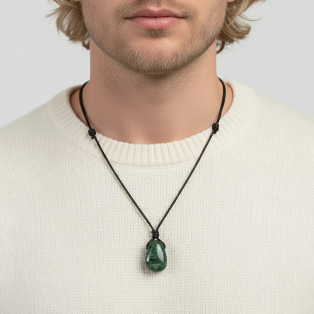 Man wearing a necklace with a green diopside pendant on a plain background