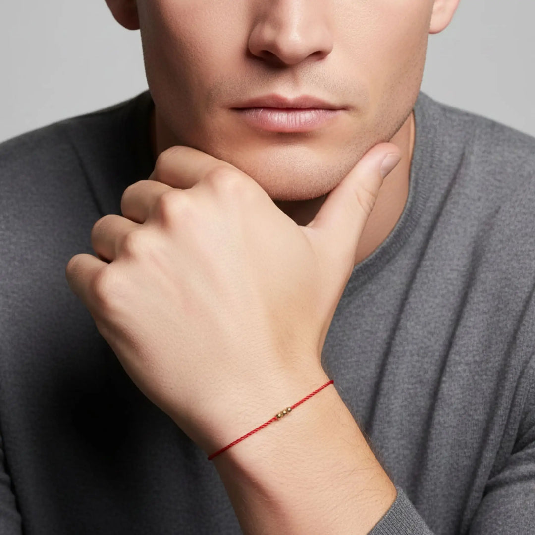 Man wearing a red bracelet on his wrist, with a neutral background