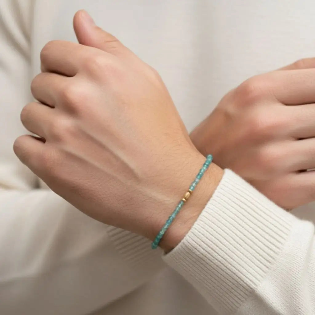 Hand wearing a paraiba tourmaline bracelet with a plain background
