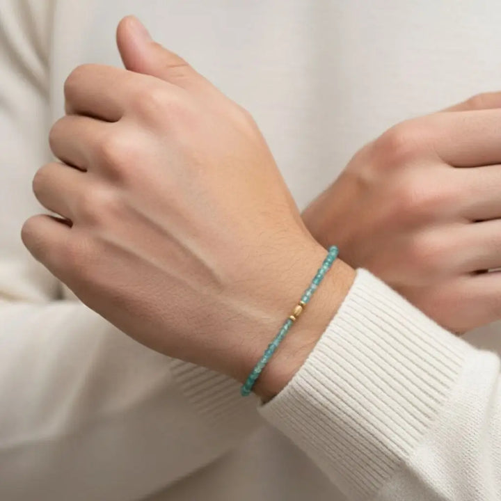 Hand wearing a paraiba tourmaline bracelet with a plain background