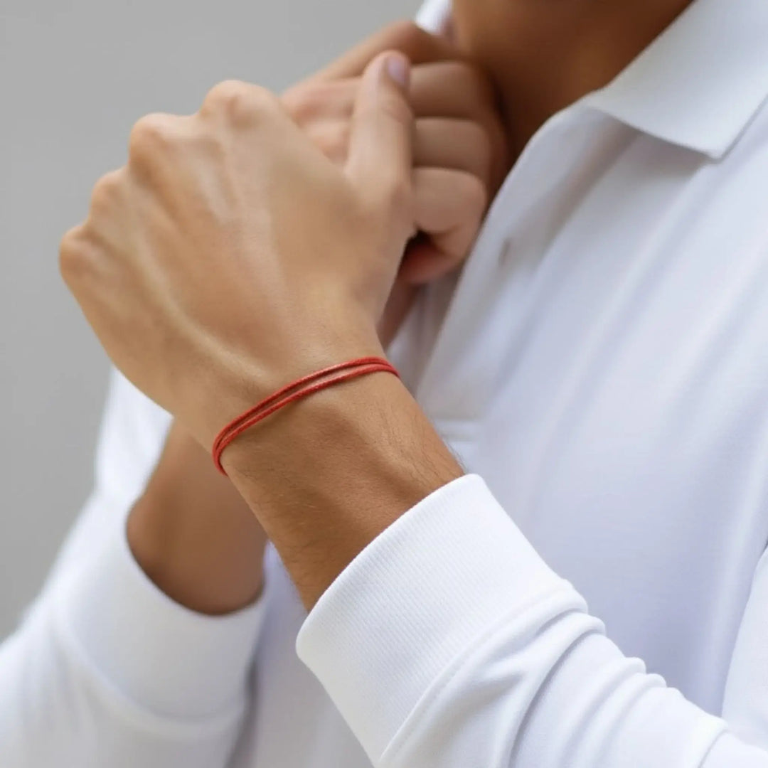 Person wearing a white shirt with a red bracelet on a neutral background