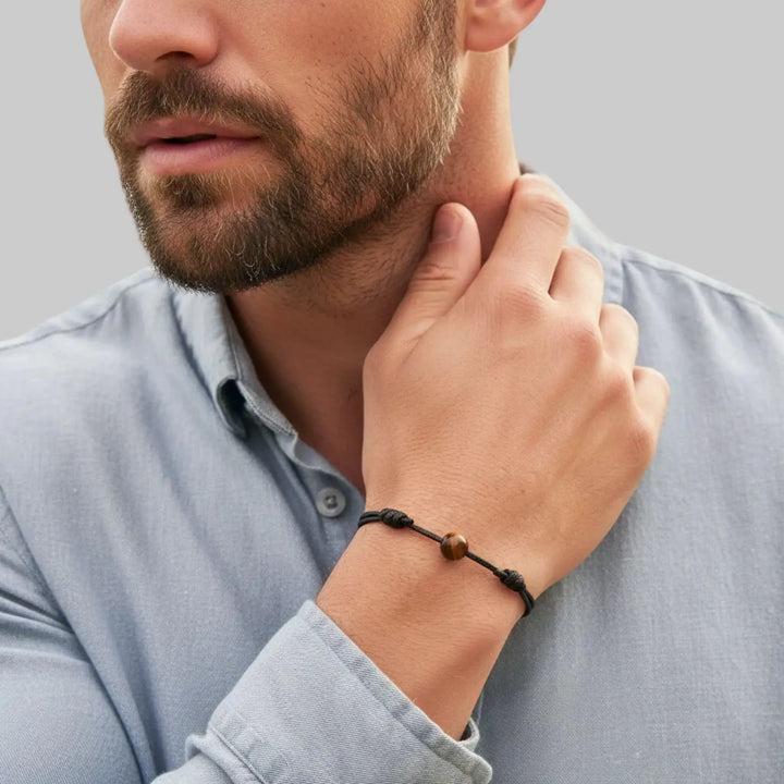 Man wearing a tiger eye bracelet on his wrist with a blurred background