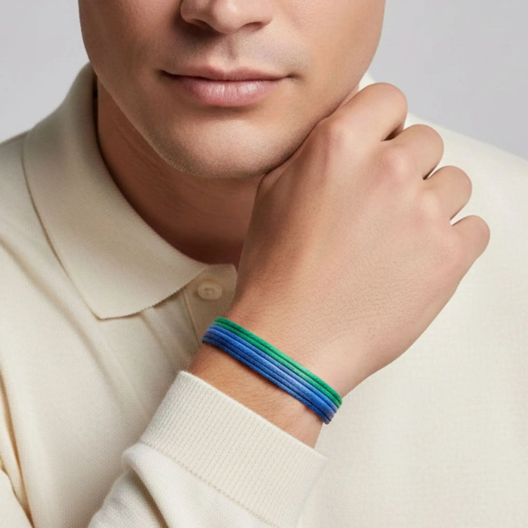 Person wearing a blue and green bracelet on a plain background