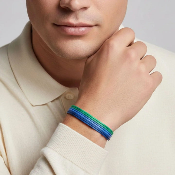 Person wearing a blue and green bracelet on a plain background