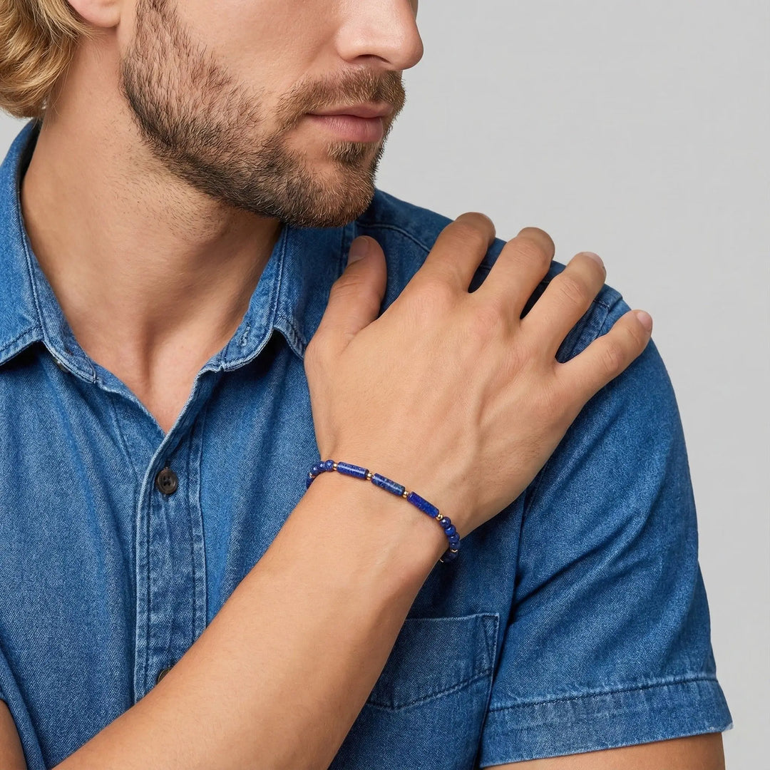 Man wearing a blue denim shirt with a close-up of his hand and lapis lazuli bracelet on a light gray background