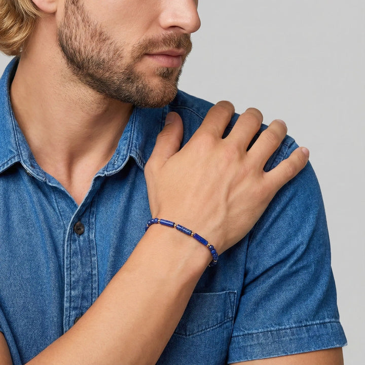 Man wearing a blue denim shirt with a close-up of his hand and lapis lazuli bracelet on a light gray background