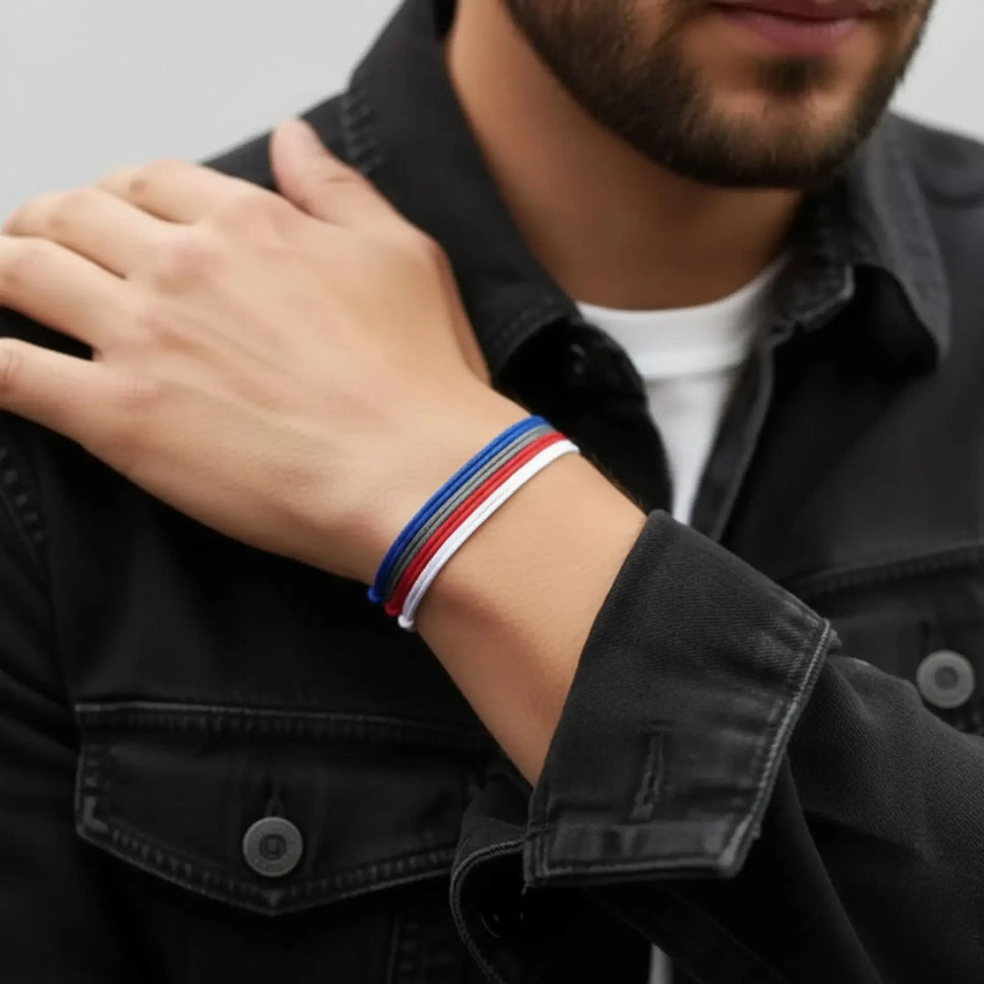 Person wearing a black jacket with a colorful bracelet on a neutral background