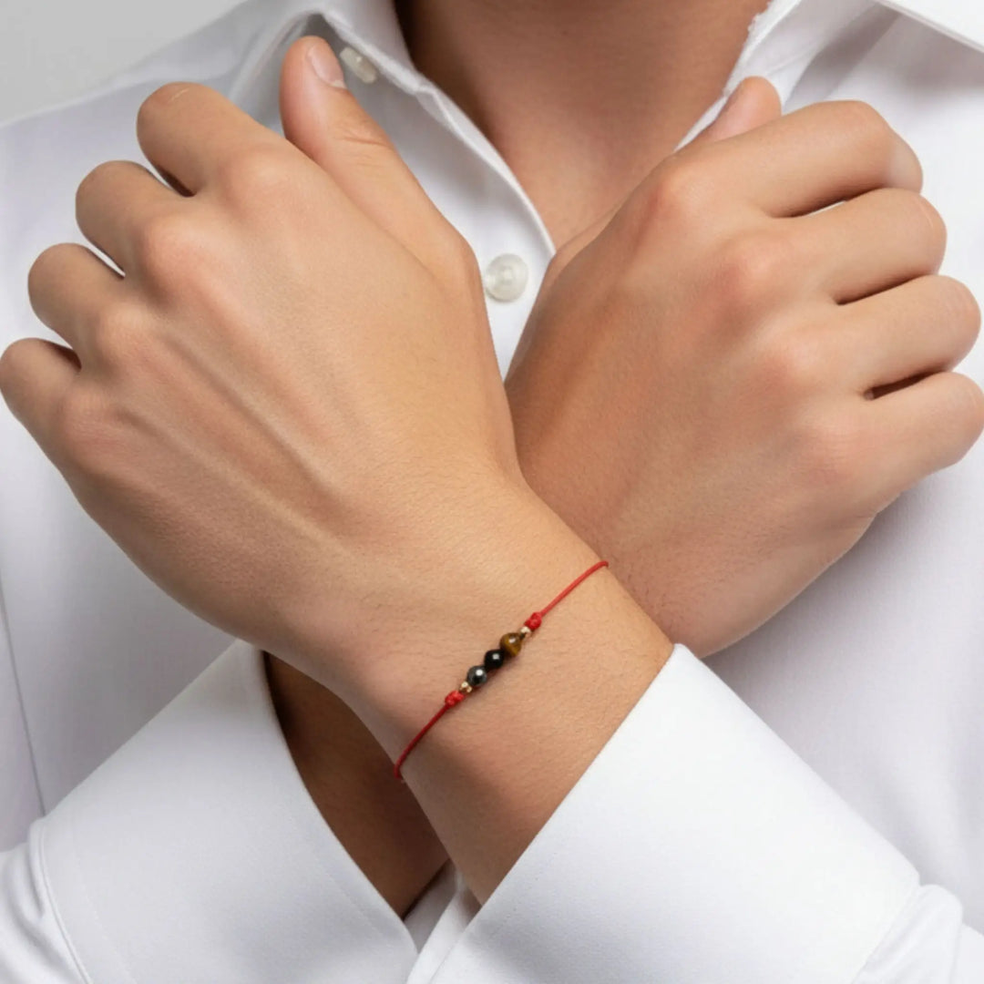 Close-up of a person wearing a red string bracelet with beads on a white background