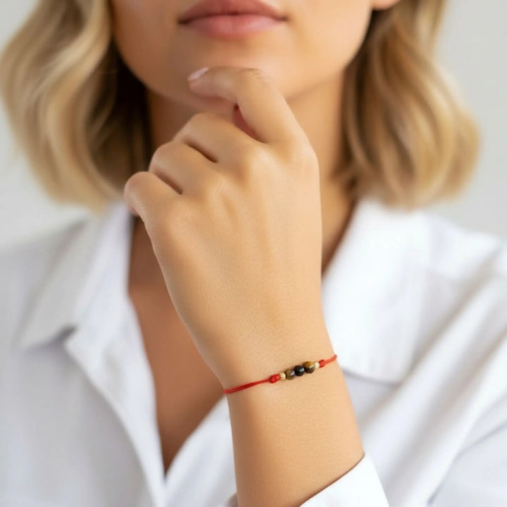 Person wearing a red bracelet on a neutral background