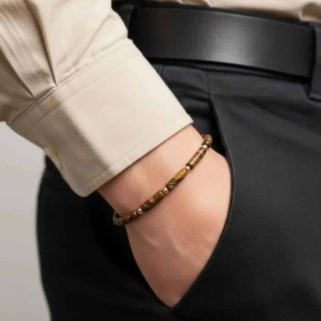Person wearing a tiger eye bracelet with a neutral background