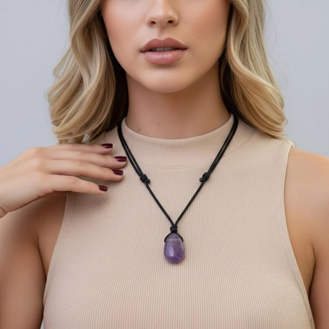 Woman wearing a necklace with a purple amethyst pendant against a neutral background