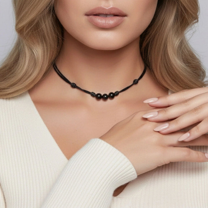 Woman wearing a black beaded necklace with a neutral background