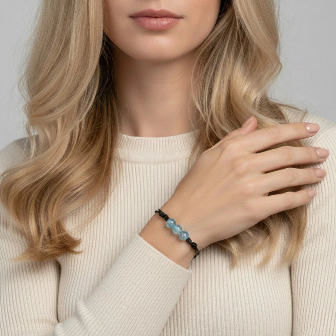 Woman wearing a bracelet with blue beads on a plain background