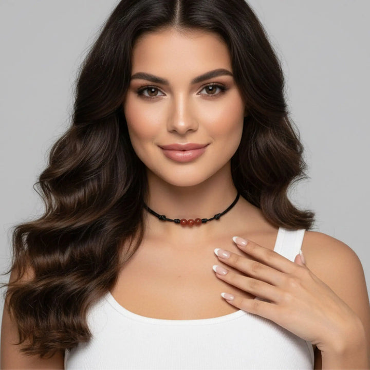 Woman wearing a carnelain necklace with a gray background