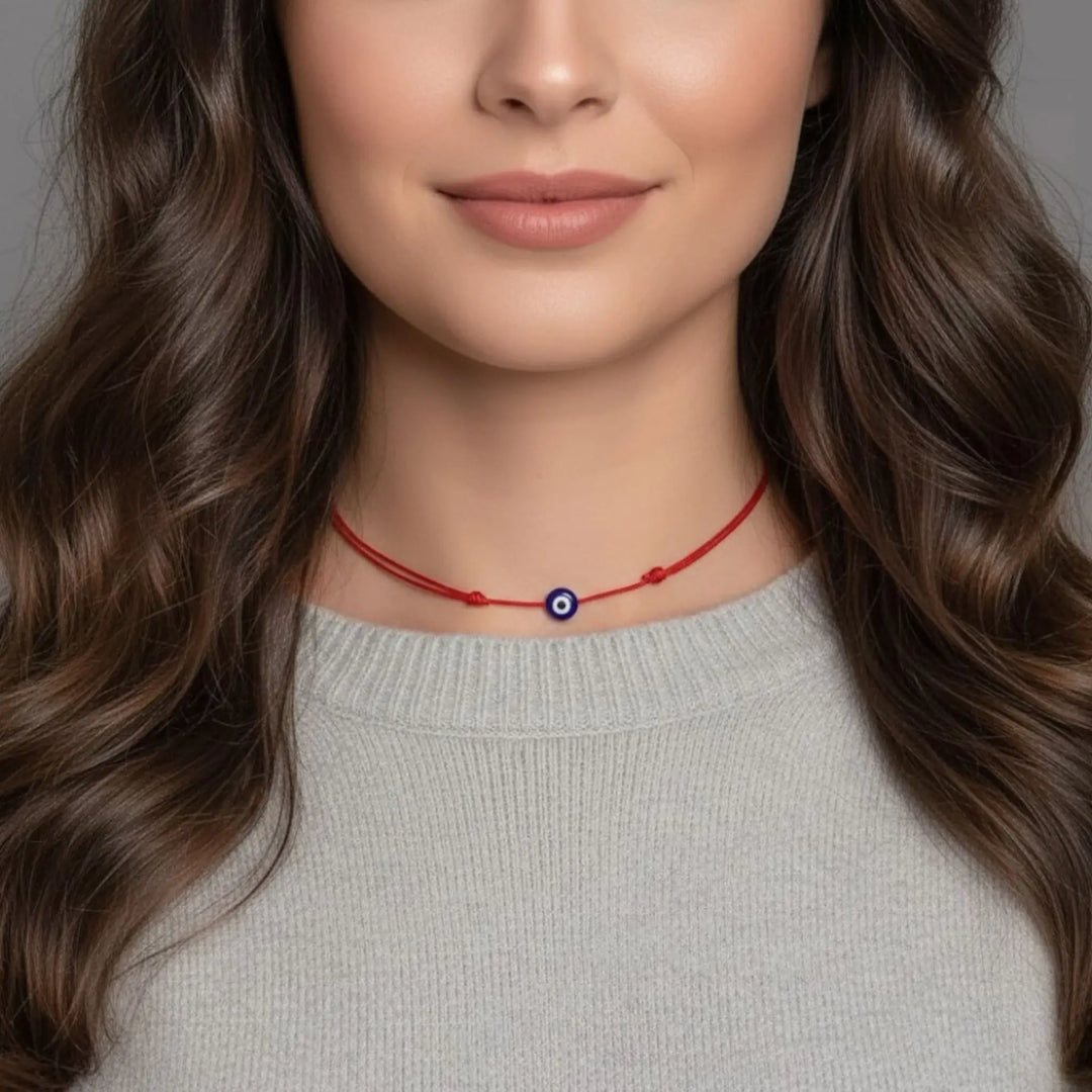 Woman wearing a red necklace with an evil eye pendant on a neutral background