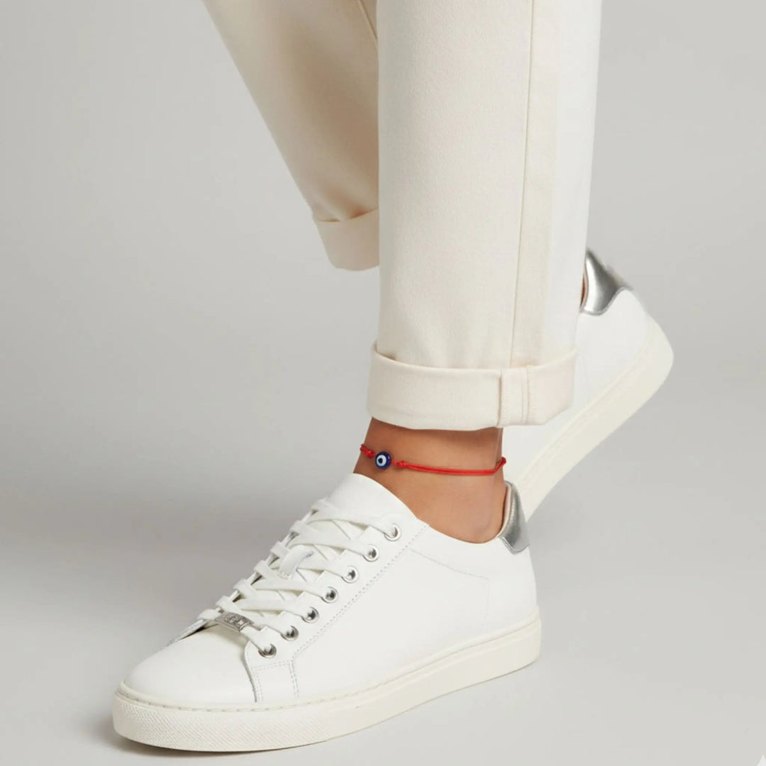 White sneakers worn with beige pants on a plain background