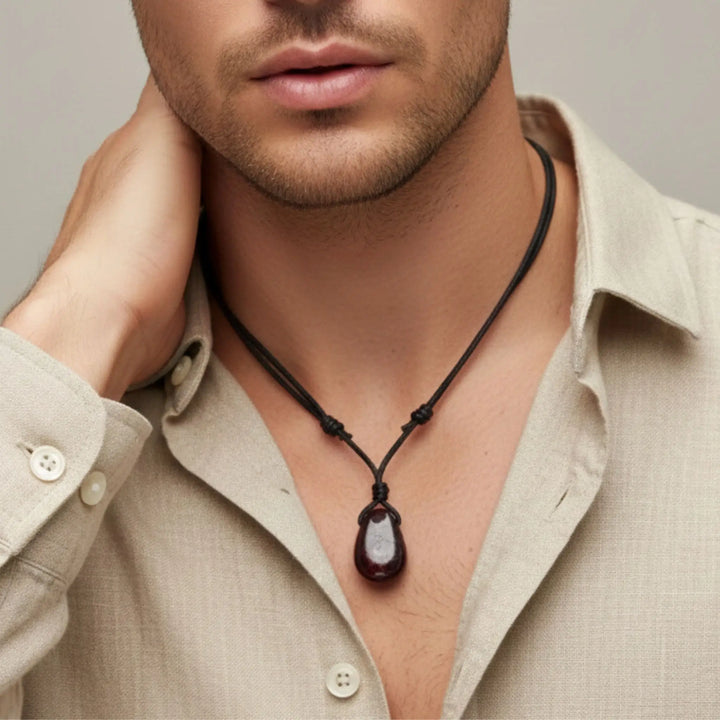 Man wearing a necklace with a pendant against a neutral background