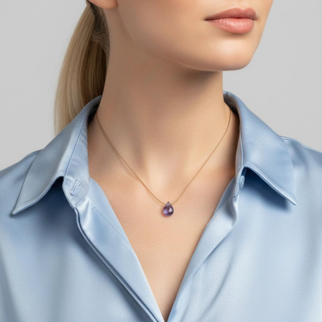 Necklace with a tanzanite pendant worn by a person in a light blue shirt against a neutral background
