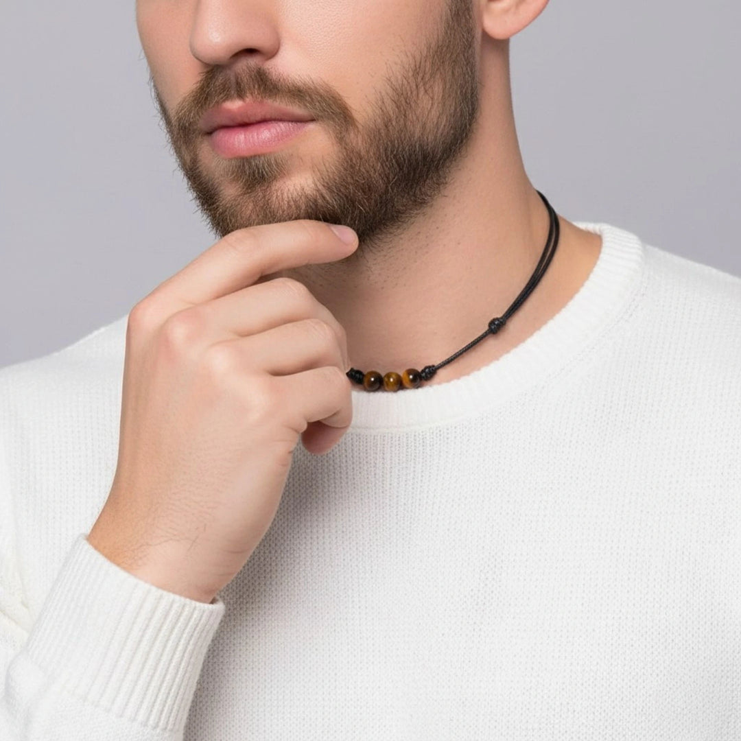 Man wearing a black beaded necklace against a gray background