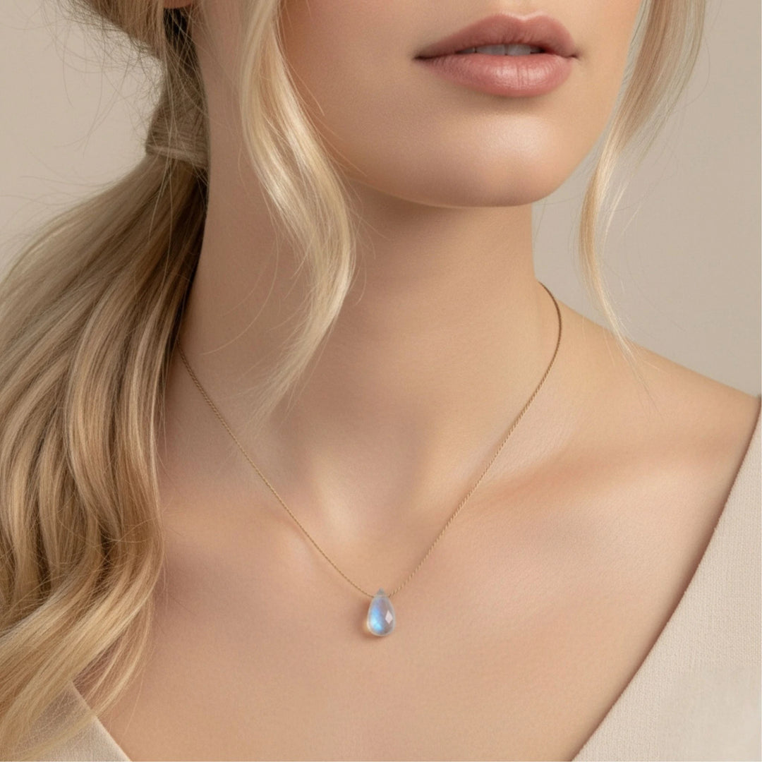 Necklace with a moonstone teardrop pendant worn by a model with blonde hair.