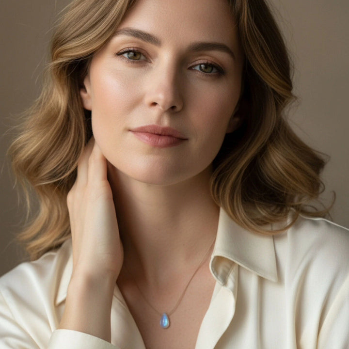 Woman wearing a moonstone necklace with a pendant against a neutral background