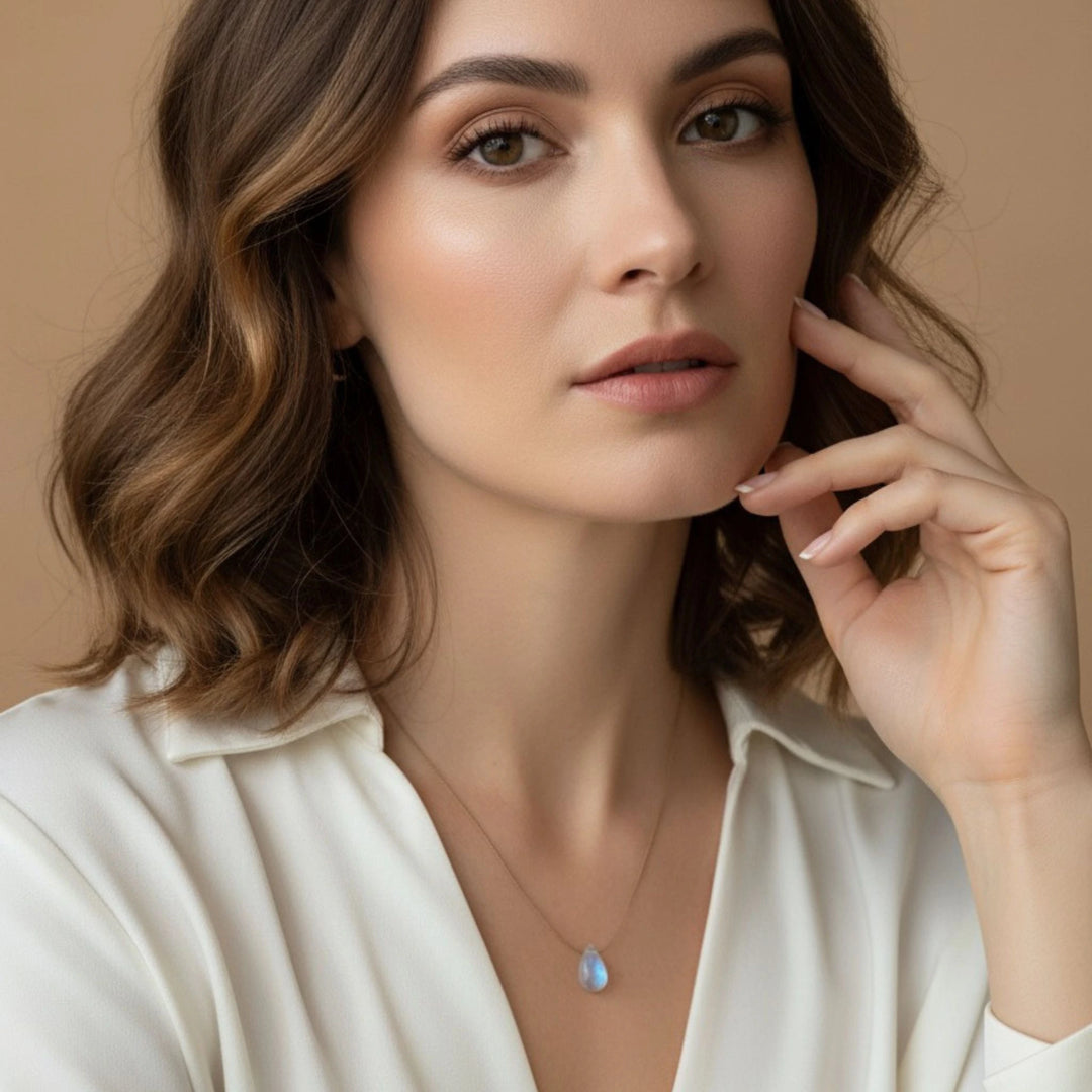 Woman wearing a necklace with a moonstone pendant against a beige background