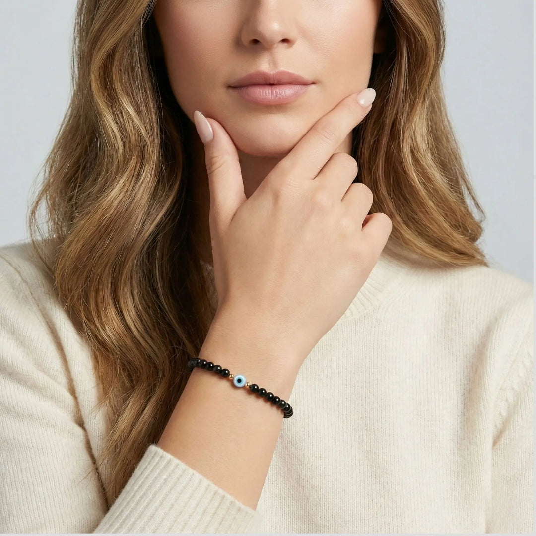 Woman wearing a black tourmaline beaded bracelet on a plain background