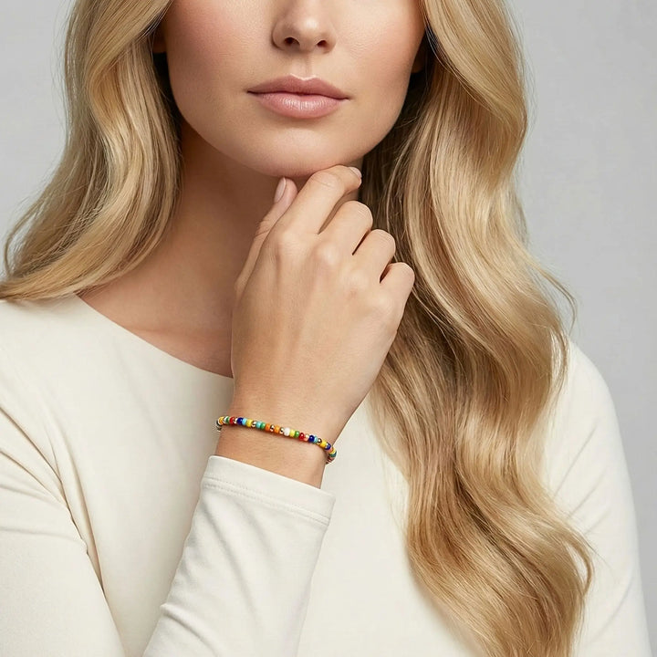 Woman with long blonde hair wearing a colorful beaded bracelet on a neutral background