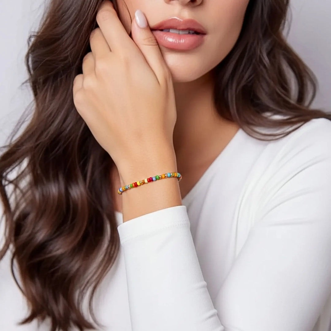 Woman wearing a colorful beaded bracelet on a plain background