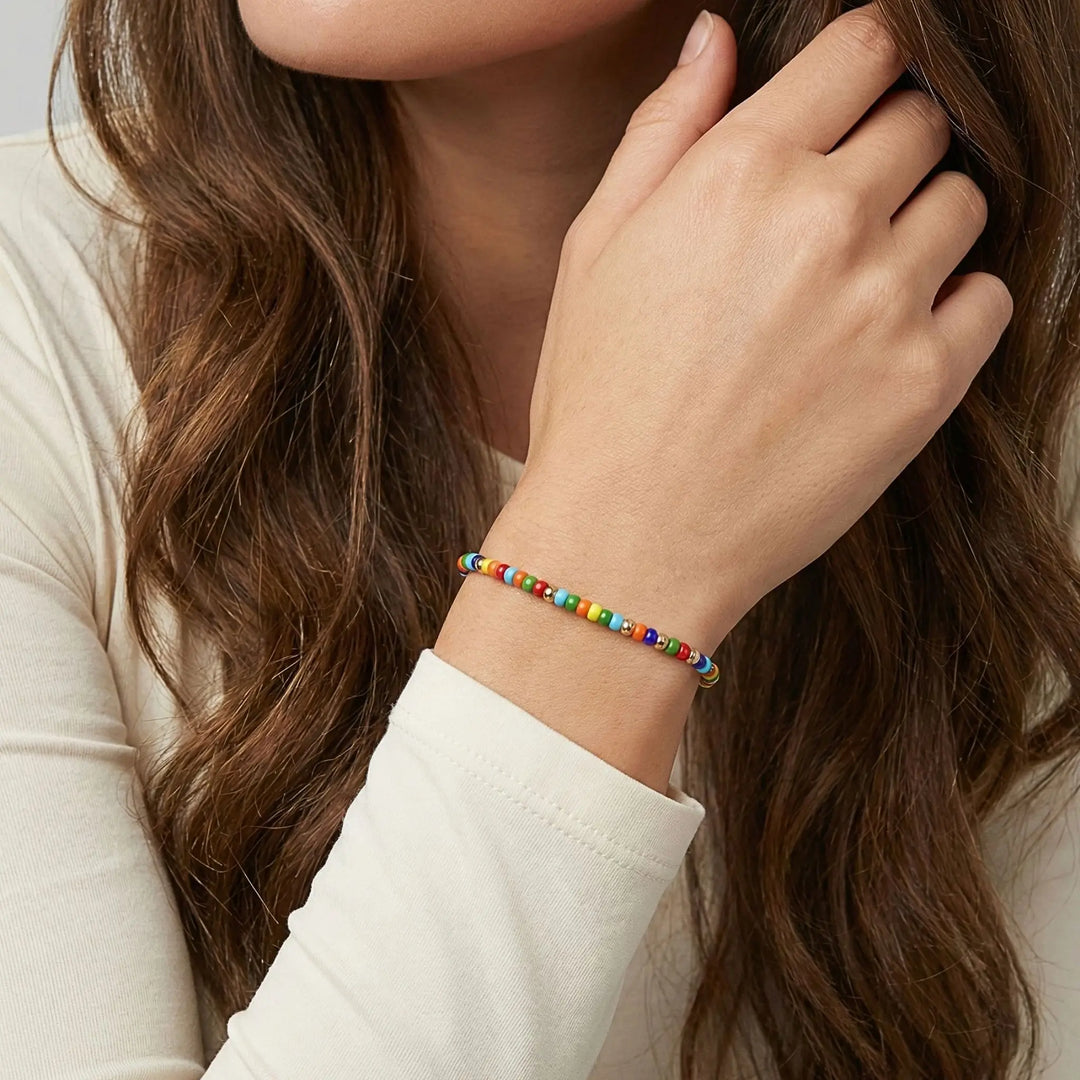 Close-up of a person wearing a colorful beaded bracelet on a neutral background