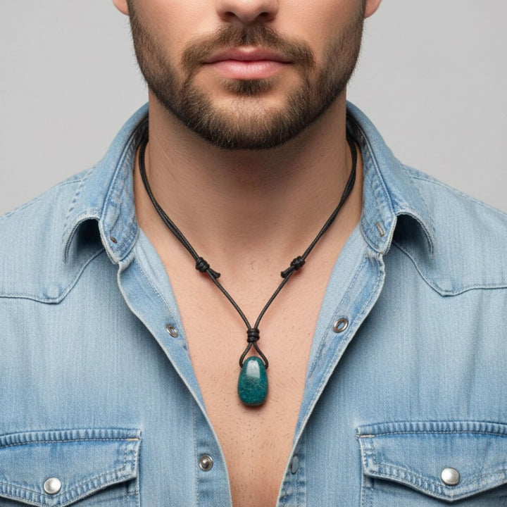 Man wearing a blue denim shirt with an Apatite necklace featuring a green pendant against a gray background