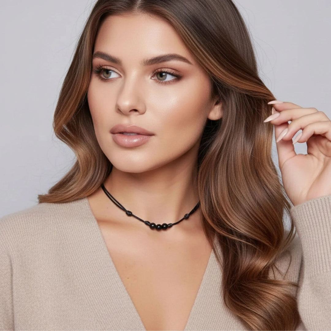Woman with styled hair and a neutral background wearing a black tourmaline choker.