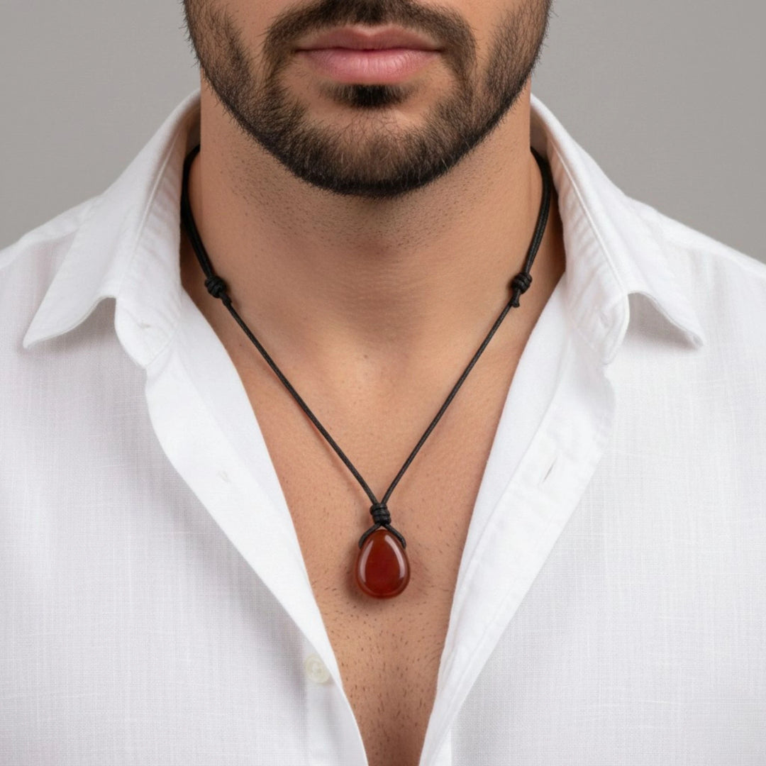 Man wearing a white shirt with a necklace featuring a carnelian pendant against a gray background
