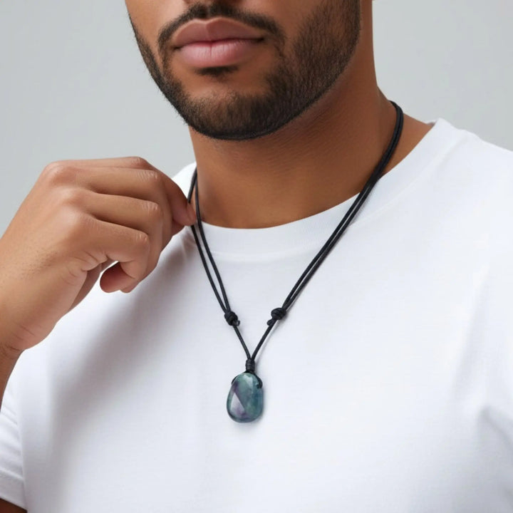 Man wearing a necklace with a fluorite pendant against a neutral background
