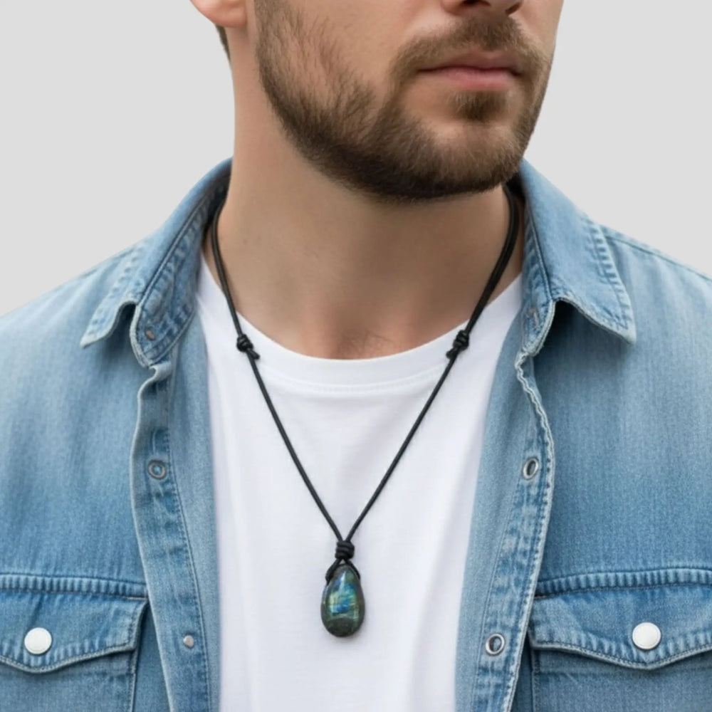 Man wearing a denim jacket and white shirt with a necklace featuring a green pendant.