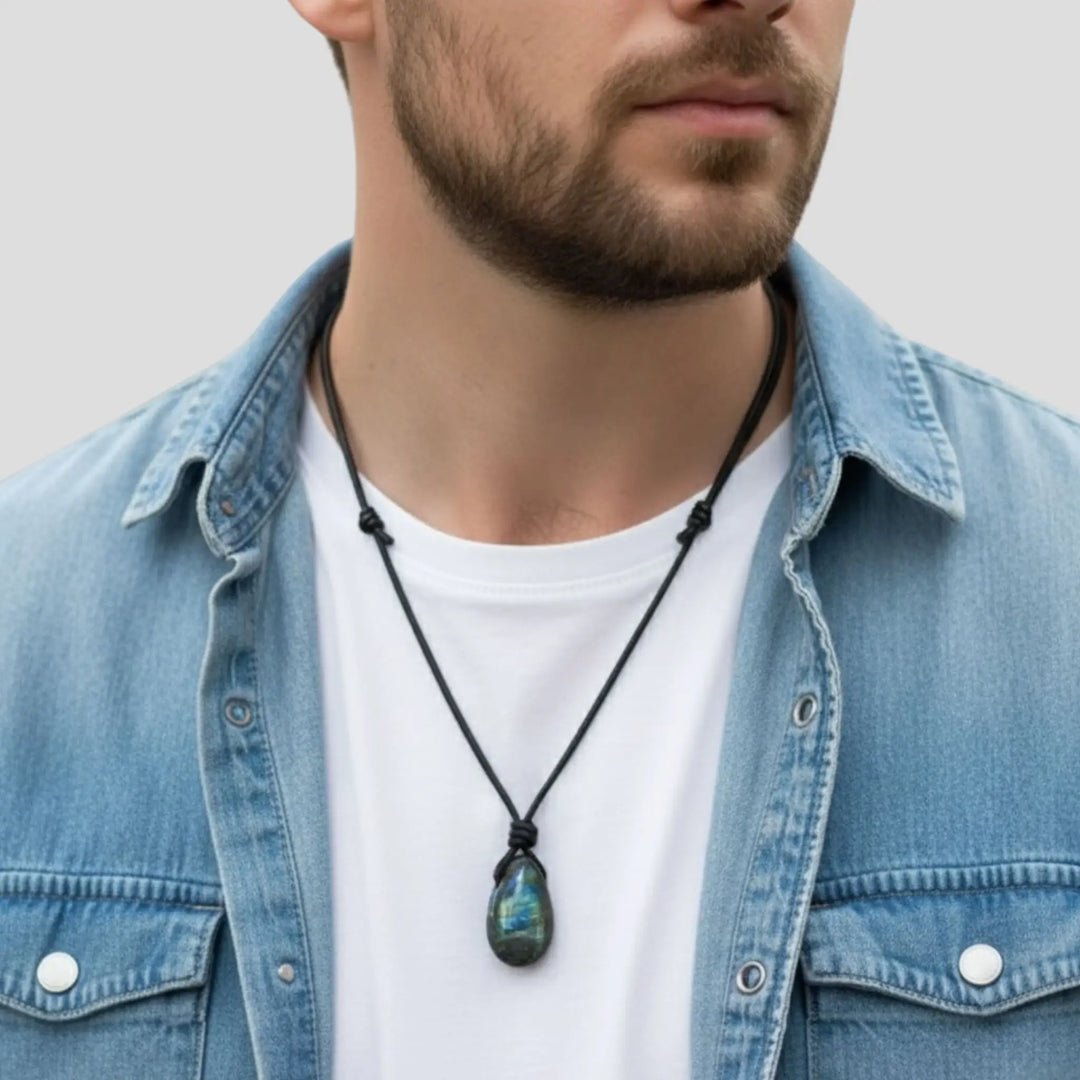 Man wearing a denim jacket and white shirt with a necklace featuring a green pendant.
